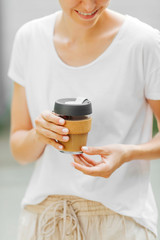 Female hands hold reusable coffee mug. Take your coffee to-go with reusable travel mug. Zero waste. Sustainable lifestyle concept..