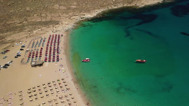Aerial drone video of famous organised with sun beds and umbrellas beach of Lia with emerald clear sandy sea shore, Mykonos island, Cyclades, Greece  