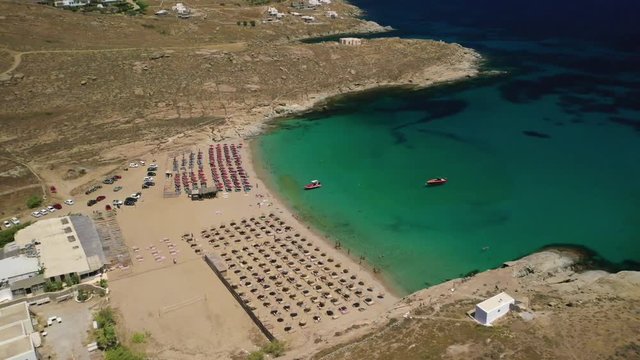 Aerial drone video of famous organised with sun beds and umbrellas beach of Lia with emerald clear sandy sea shore, Mykonos island, Cyclades, Greece  