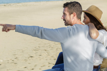mid-adult couple at the beach man pointing forwards