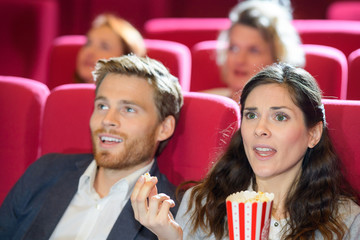 young couple at the cinema watching an horror movie