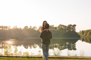 People, love and nature concept - Young beautiful woman and handsome man embracing each other over water background