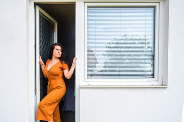 young woman opens pvc balcony  door with jalousie near pvc window