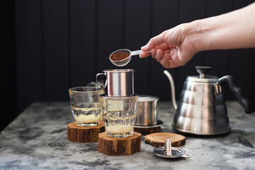 Making pour over coffee with condensed milk Vietnamese style. Woman hand pouring ground coffee into...