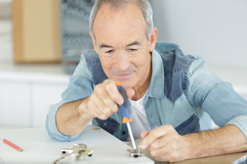 senior man assembling kitchen cupboard using screwdriver