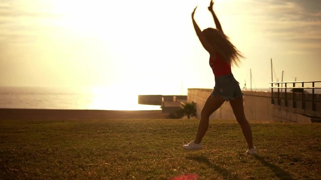Happy girl jumps and doing cartwheels on beach enjoying sunset on summer travel vacation. Happiness concept. SLOW MOTION
