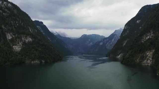Aerial dark cinematic shot of the Konigsee lake in Bavarian Alps, Germany before the rain