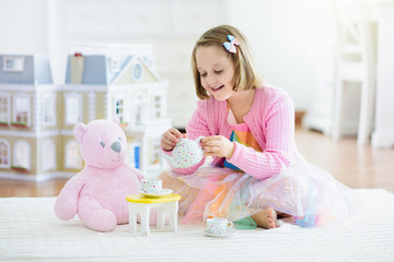 Little girl playing with doll house. Kid with toys