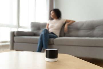Portable wireless speaker on table with african woman on background