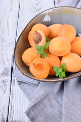 Ripe apricots in a ceramic bowl on the white table
