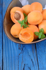 Ripe apricots in a ceramic bowl on the blue table