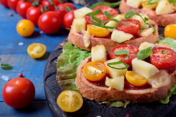 Bruschetta with different sorts of cherry tomatoes and soft cheese on the blue table