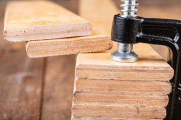 A small joinery clamp used for gluing planks. Accessories for carpenters on the workshop table.