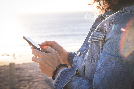 Close up view of a woman watching social video online. Girl communicate with remote friends with smartphone near a beautiful beach Hands typing on phone New trends technology and communication concept