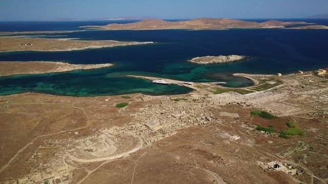 Aerial drone panoramic distant view video of famous archaeological site a whole ancient citadel in island of Delos, Cyclades, Greece