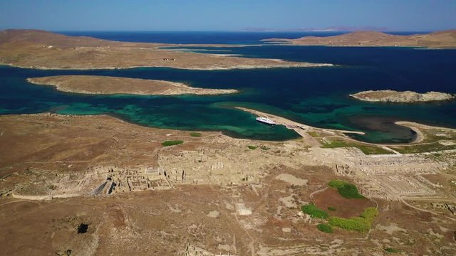 Aerial drone panoramic distant view video of famous archaeological site a whole ancient citadel in island of Delos, Cyclades, Greece