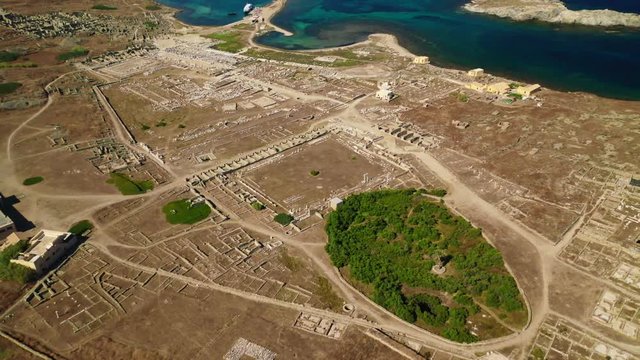 Aerial drone panoramic distant view video of famous archaeological site a whole ancient citadel in island of Delos, Cyclades, Greece