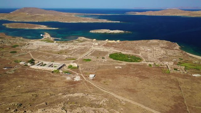 Aerial drone panoramic distant view video of famous archaeological site a whole ancient citadel in island of Delos, Cyclades, Greece