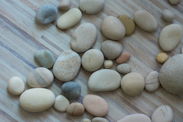 Fototapeta na wymiar Group of white, grey and light brown stones on white light wooden background, pebbles beach