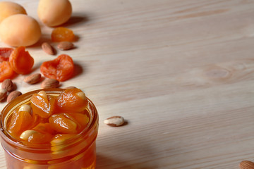 Jar of sugar-free fruit confiture homemade healthy jam with dried and raw apricots and nuts wooden background table with copy space
