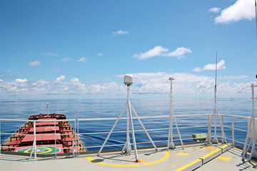 Blue sky and clouds in the open ocean. Views of the ship's mast and antennas on the navigation deck.