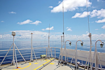 Blue sky and clouds in the open ocean. Views of the ship's mast and antennas on the navigation deck.