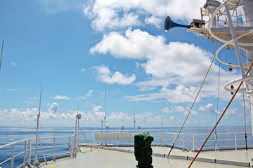 Blue sky and clouds in the open ocean. Views of the ship's mast and antennas on the navigation deck.