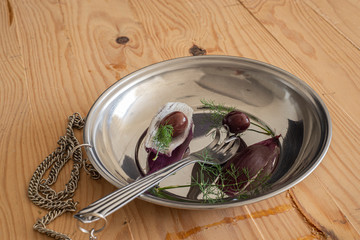 Fork deformed like a human hand, olives, dill, and red onions