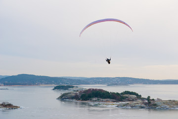 Paraglider gliding over an ice cold fjord.