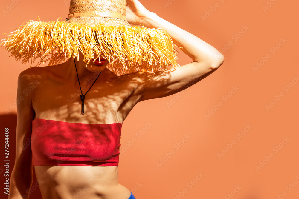 Wall mural young woman wearing straw hat with fringe and swimsuit having fun over bright background, shorts, su