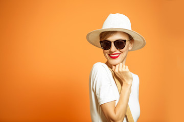 Fashionable woman in a hat and sunglasses, accessories, posing in studio over vibrant color background, copy space. Fashion summer	