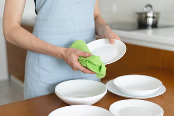 Woman cleaning plates and bowls on kitchen with wooden table