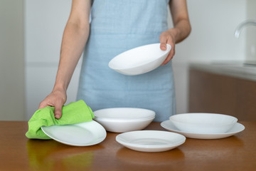 Obraz na płótnie Canvas Woman cleaning plates and bowls on kitchen with wooden table