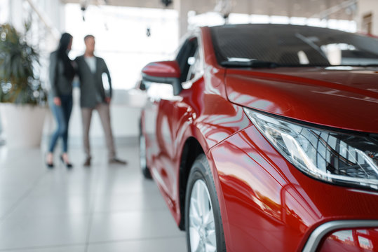 Couple buying new red car in showroom