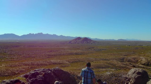 Hikers Enjoy View On Top Fly Over Aerial. aerial view flying over people on top of a rock formation in the middle of southwest desert scene