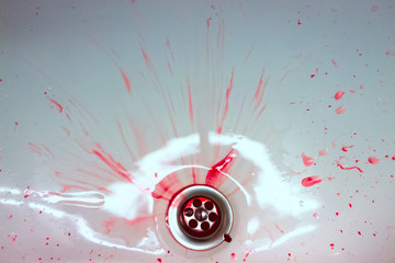 Red drops and blood stains on a white surface. The concept of bloody suicide and disease