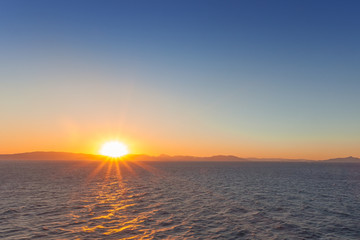 Fototapeta premium Sun about to set behind the profile of the Saronic Gulf islands