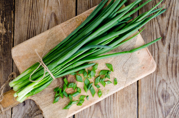 Bunch of fresh green onions on wooden table.