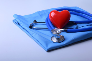 Doctor coat with medical stethoscope and red heart on the desk