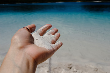 Coral white sand strewing from hand at fraser island australia