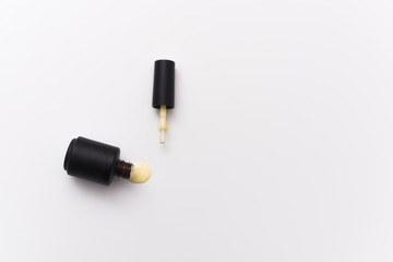 Fototapeta premium yellow gel nail polish in a black bottle on a white background. Manicure concept for blogs and design templates