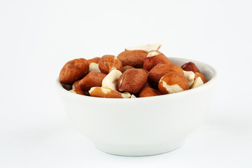 Fototapeta na wymiar Pile of raw unpeeled peanut in white ceramic bowl on white background