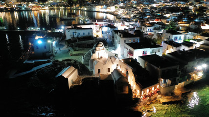 Aerial drone night shot of iconic and picturesque illuminated Little Venice in main town of Mykonos island nect to famous chapel of Paraportiani, Cyclades, Greece