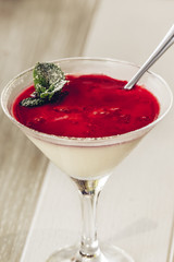 Photo of italian panna cotta dessert with strawberry sirup and mint leaf, soft focus