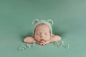 Sleeping newborn baby on a green background. Photoshoot for the newborn. A few days from birth. - obrazy, fototapety, plakaty