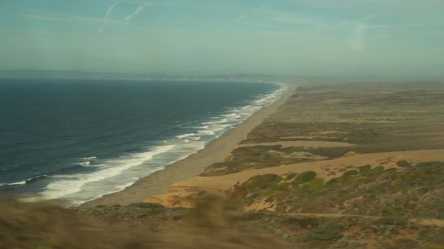 Beautiful, wide beach by the seaside. Cloudless, sunny day of summer. Shot is taken drom a driving car.