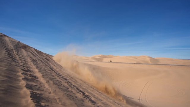 Slow motion shot of dune buggy drifting on a desert. Bright, sunny day.