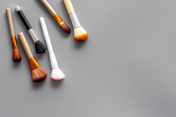Women desk with brushes for make up on gray background flat lay space for text