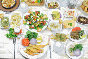 Greek food background. Meze, gyros, fried squid rings, souvlaki, uzo, fish, pita, greek salad, tzatziki, assortment of feta, olives and vegetables. Traditional different greek dishes set.