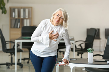 Mature woman suffering from heart attack in office